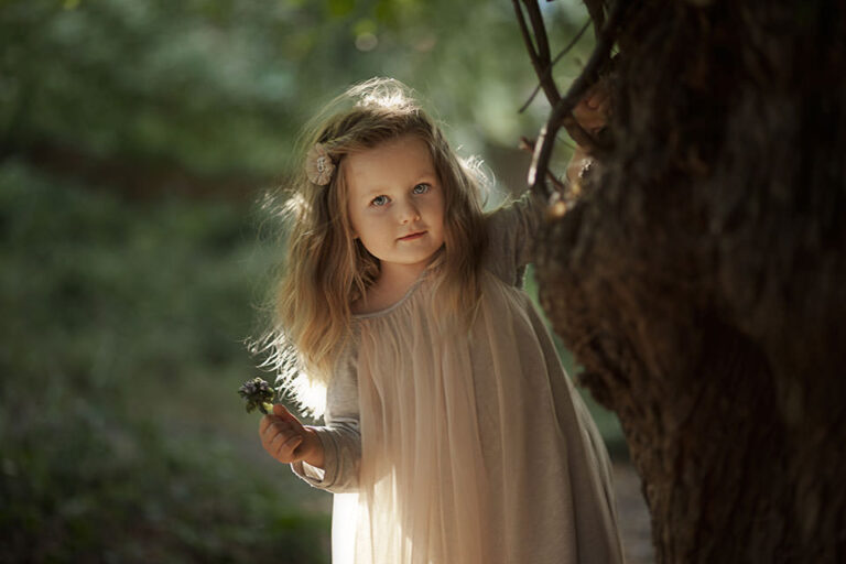 Kids Photography London | stunning backlit outdoor portrait of a girl holding a small bunch of spring flowers