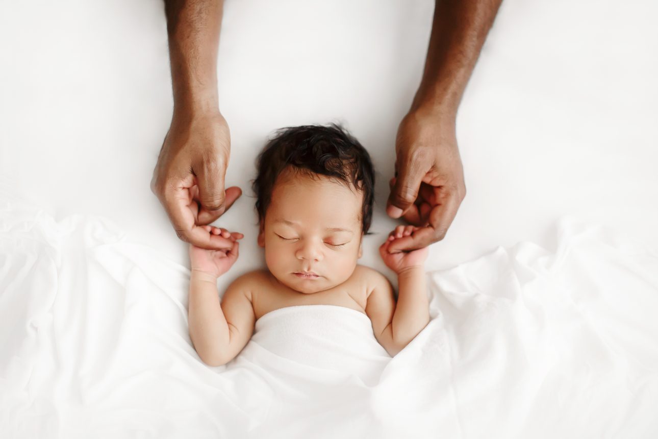 Bromley Newborn Photographer | timeless portrait of a newborn baby boy holding his dad's hands