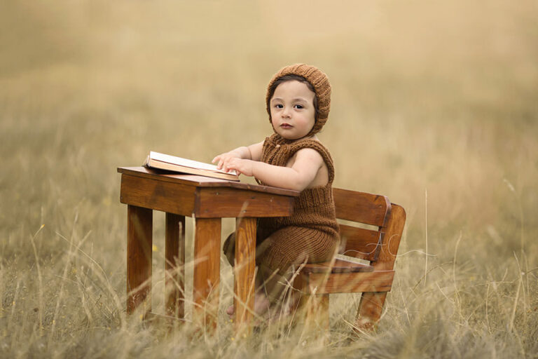 Professional South East London Toddler Photos | 1 year old toddler boy sits at the desk and reads a book in the park