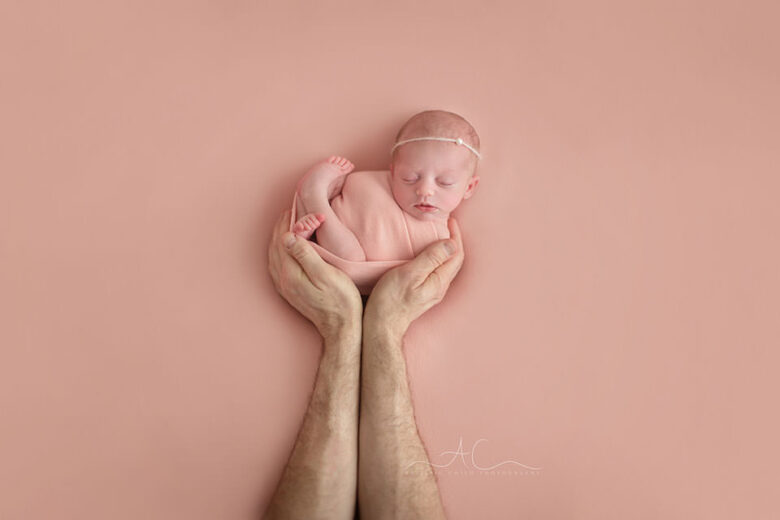 Top London Newborn Portraits | newborn baby girl sleeps in her dad's hands