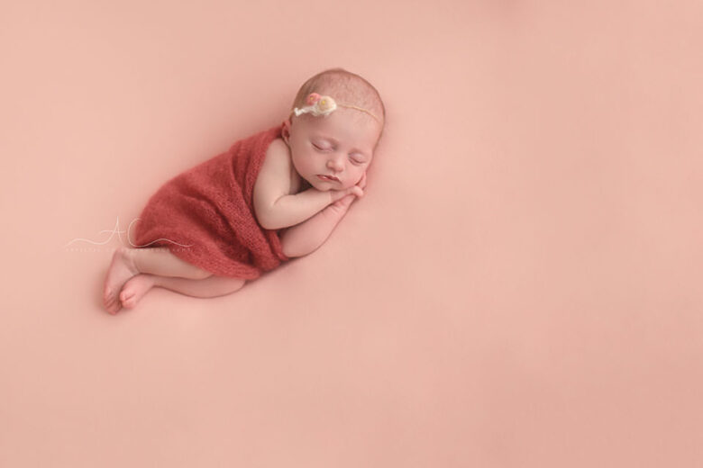 Awesome London Newborn Pictures | newborn baby girl sleeping on her side covered by hand knitted pink blanket