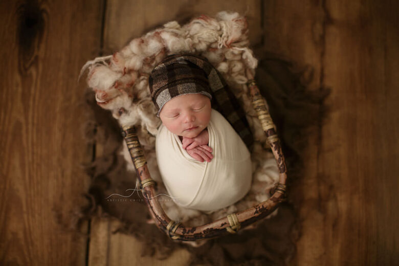 Professional South East London Newborn Baby Boy Photos | newborn baby boy wears a checked sleepy hat while sleeping in a bamboo basket