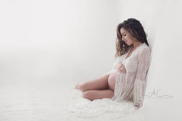 South East London Maternity Photo Session | portrait of a pregnant woman sitting on a floor and gazing at her belly