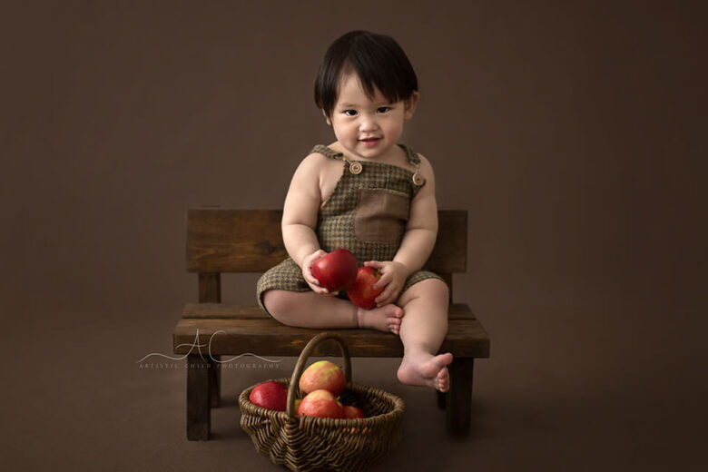 Bromley Child Photos | portrait of a 1 year old boy sitting on a wooden bench