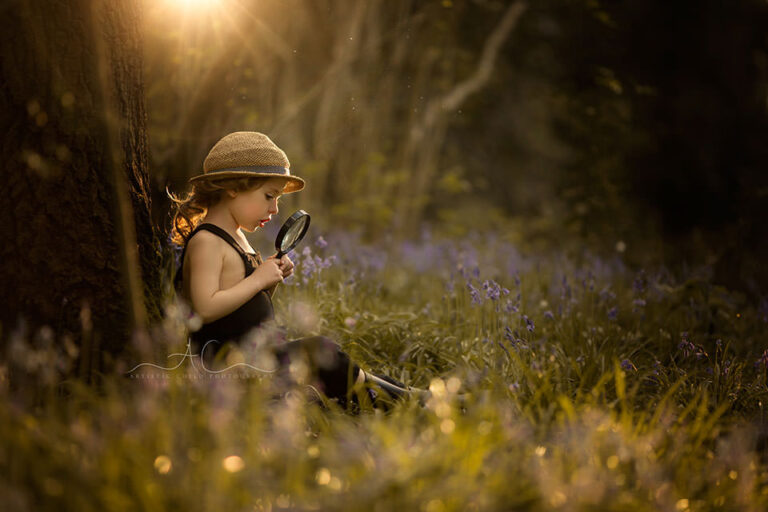 Best Spring London Children Photoshoot | backlit portrait of a 4 year old boy sitting under the tree and playing with magnifying glass