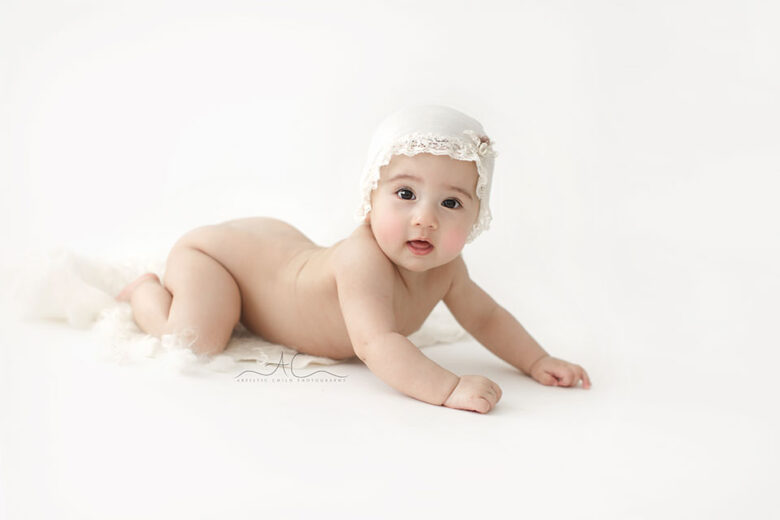 South East London Baby Girl Photographer | photo of a 7 months old baby girl on her tummy wearing a cute white sleepy hat