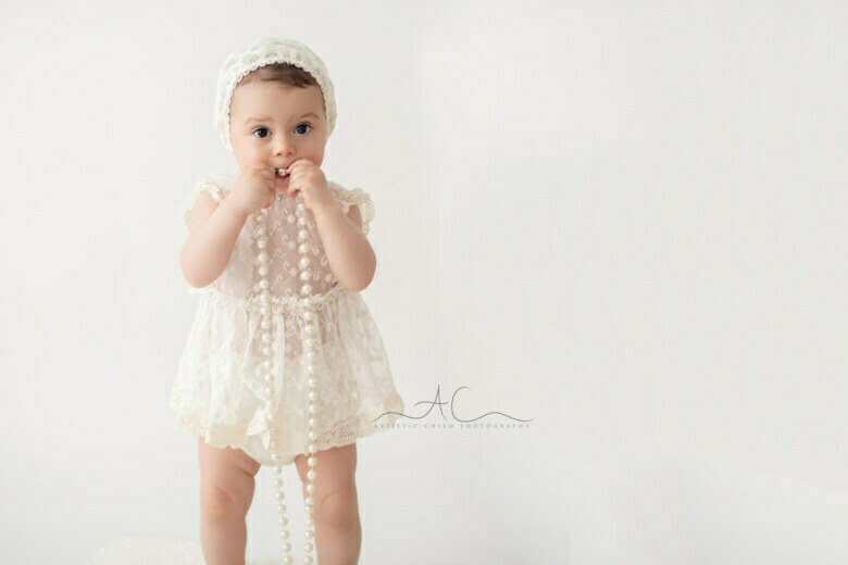 Professional South East London Toddler Photo Session | portrait of a 16 months old girl standing with pearls in her hands