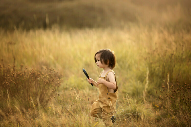 Best London Children Photos | 3 years old boy running through a long grass field with the magnifying glass