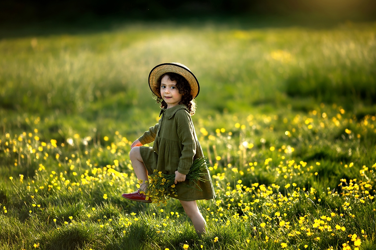 London Spring Mini Sessions | a girl walking through a wildflower field with a bunch of flowers in her hand