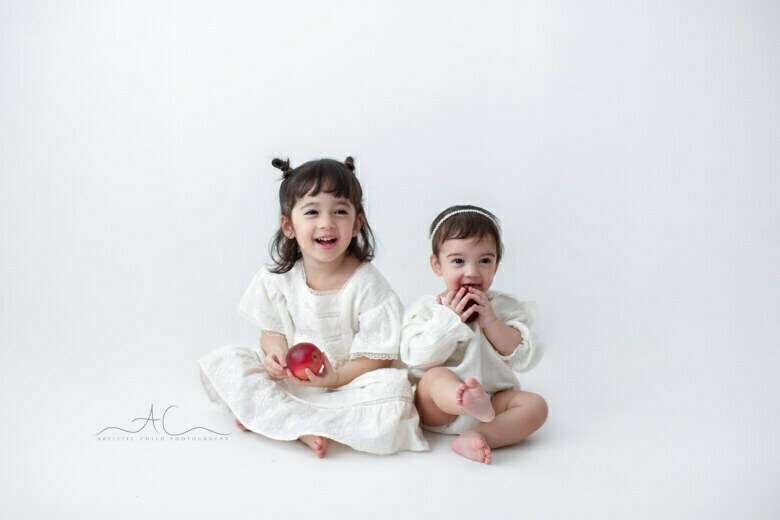Gorgeous London Sibling Portraits | photo of sisters laughting and playing with red apples