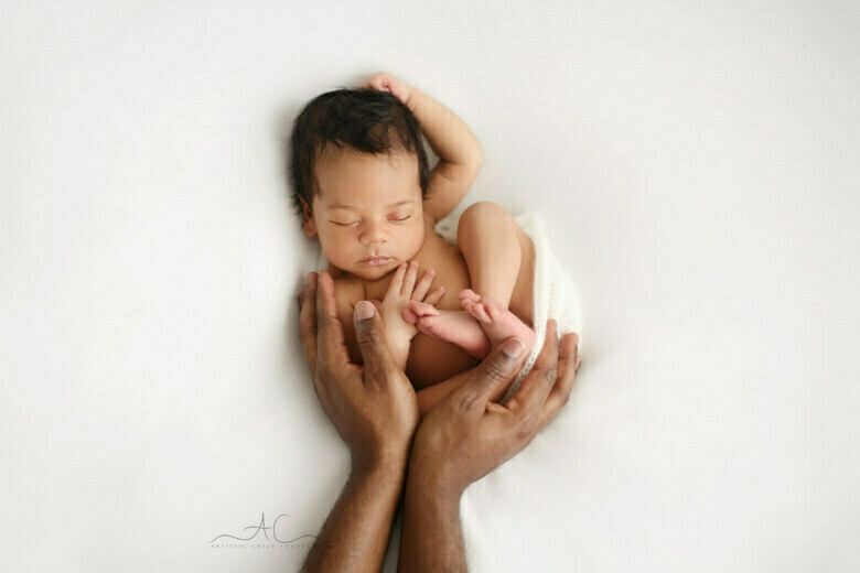 Best London Newborn Photography Services | newborn baby boy posed in Dad's hands