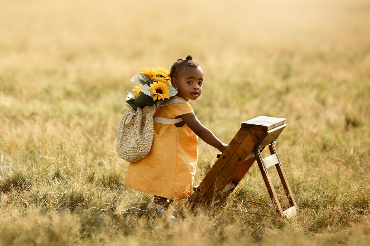 Beautiful London Toddler Photography | Dassah 2 portrait of a 1 year old girl trying to climb wooden ladder steps while carrying sunflowers on her back | London