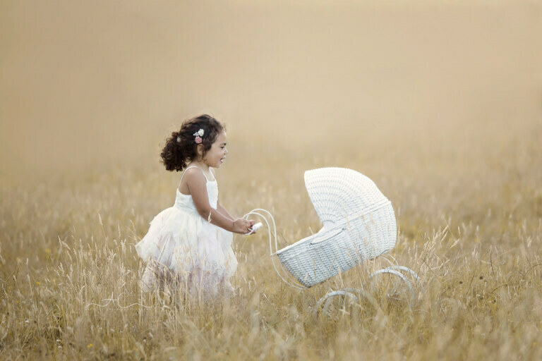 2022 Magical End Of Summer London Child Mini Sessions 2 Summer London Child Mini Sessions | 3 year old girl plays with the wicker pram in the meadow at golden hour time