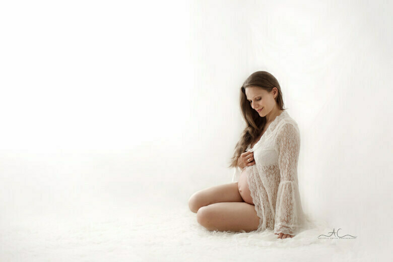 Timeless London Maternity Mini Sessions | London portrait of a pregnant woman sitting on the floor and gazing at her bump