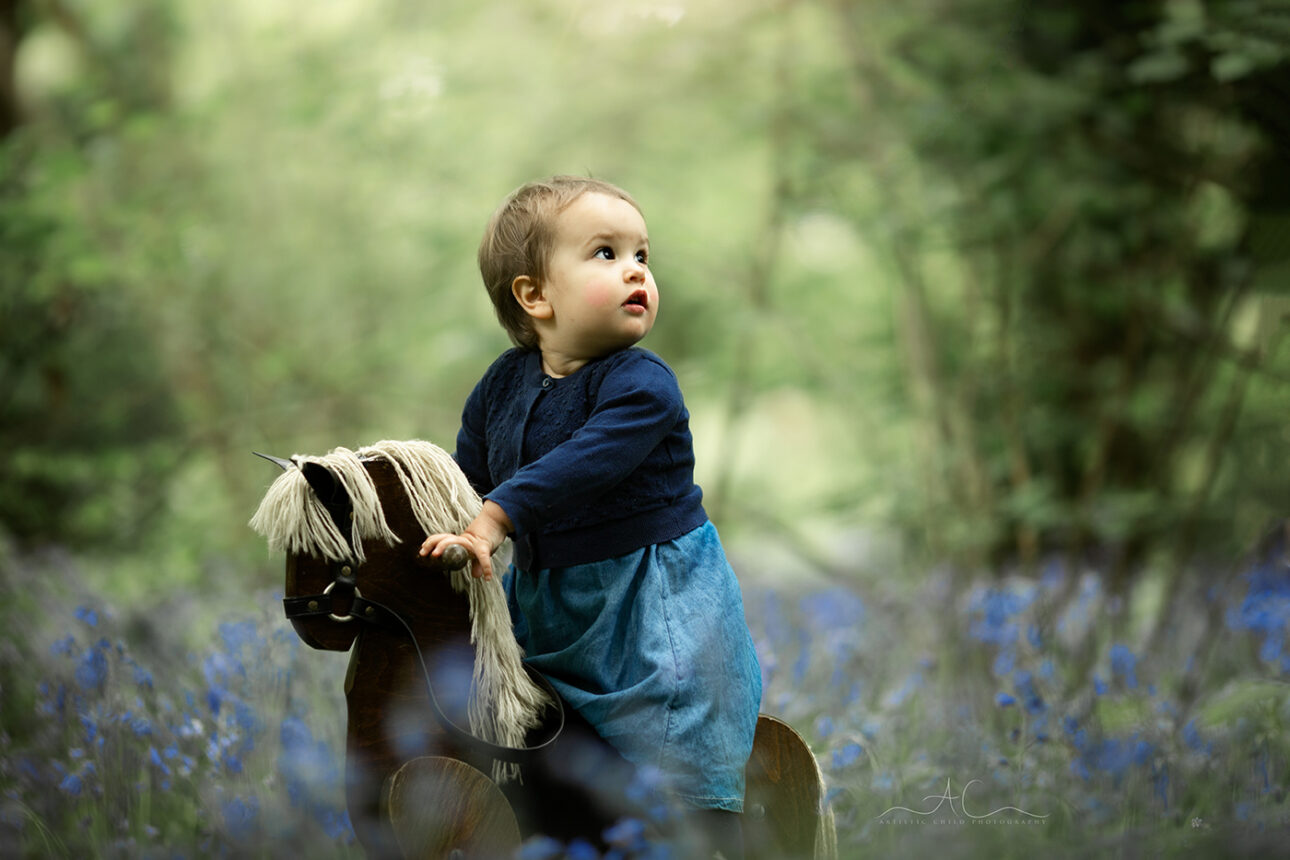 6 Magical London Toddler Bluebell Photos | Julia 4 Magical London Toddler Bluebell Photos | 1 year old girl plays with the rocking horse in the woodlands full of bluebells