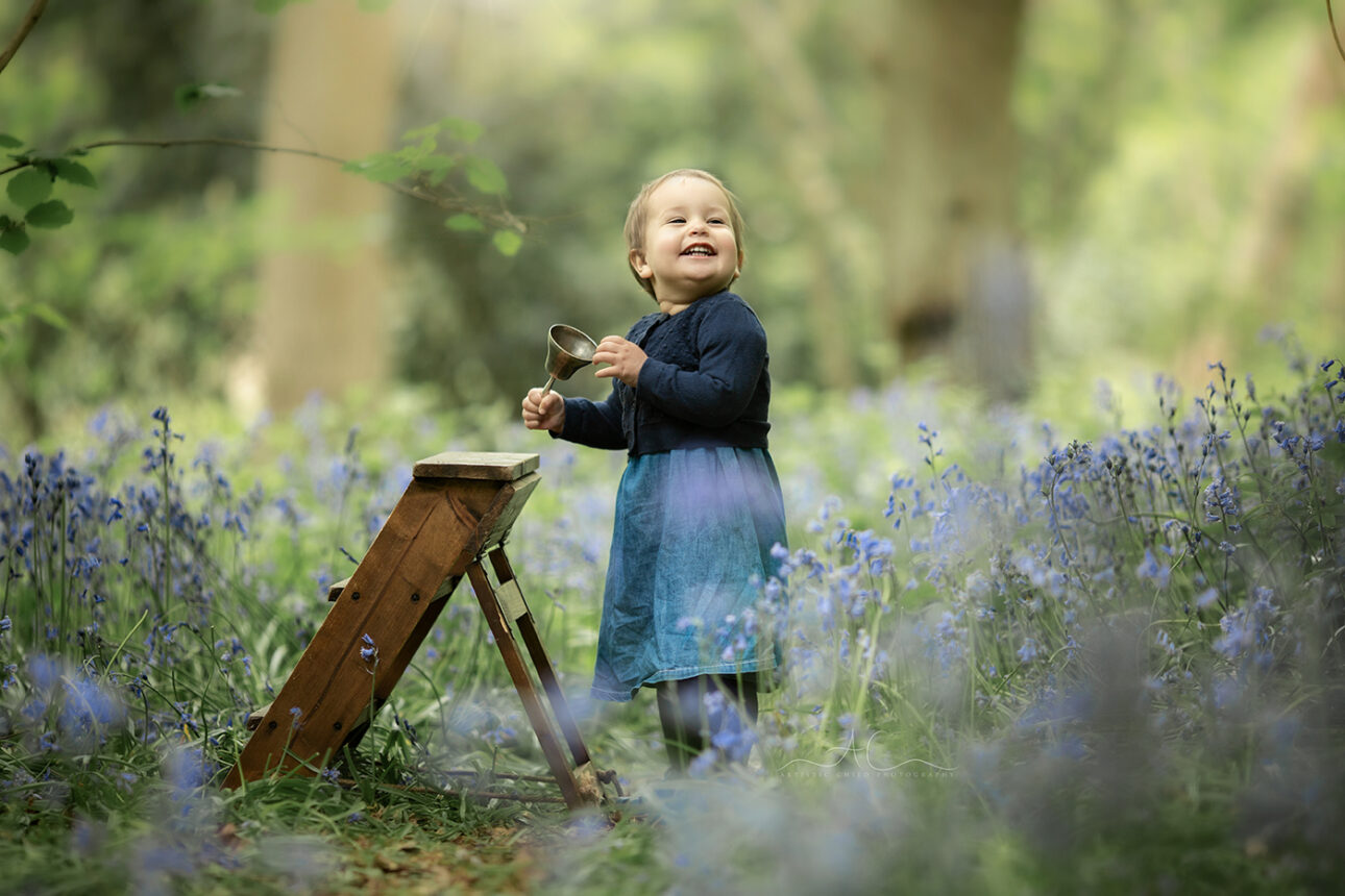 6 Magical London Toddler Bluebell Photos | Julia 6 Magical London Toddler Bluebell Photos | 1 year old girl plays with an old bell with bluebells in the background