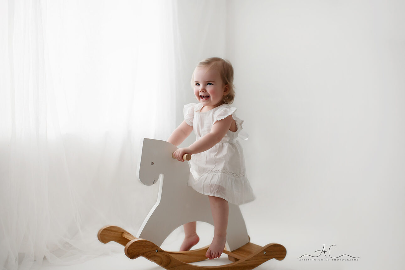 portrait of a toddler girl on a rocking horse taken during a professional photo session in a home based studio in Bromley | South East London