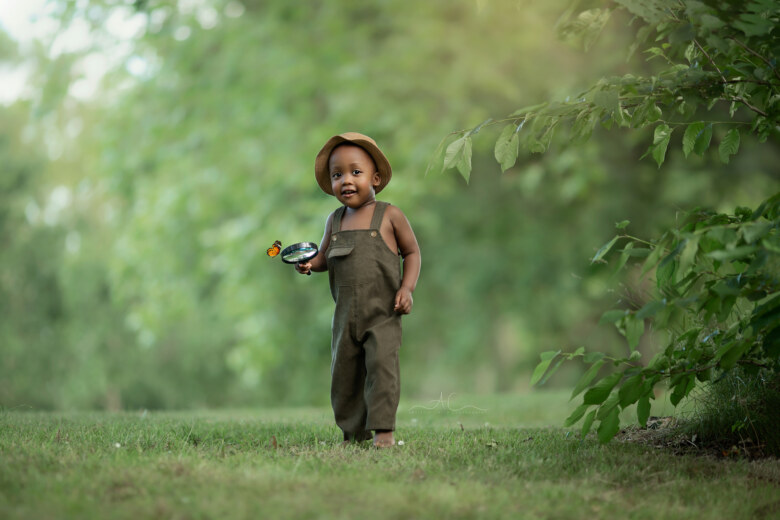 Amazing London Professional Children Portraits | portrait of a 2 year old boy playing with a magnifying glass in the park