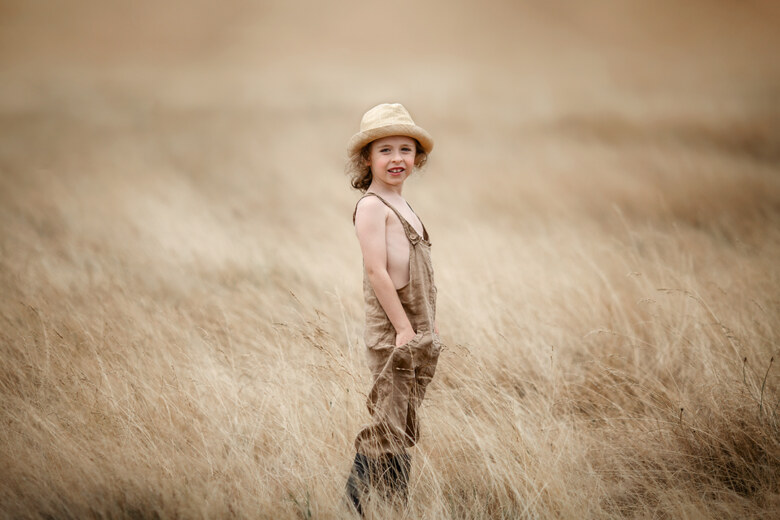 London End of Summer Children and Family Mini Sessions | portrait of a 7 year old boy wearing a straw hat in the meadow