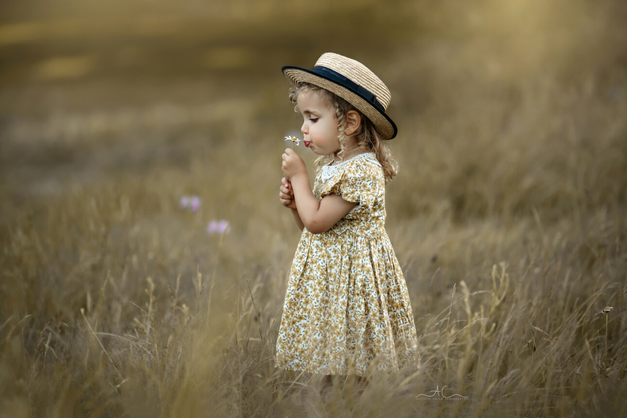 Stunning Professional London Children Images | little girl in a straw summer hat smells the cammomile flower in the park