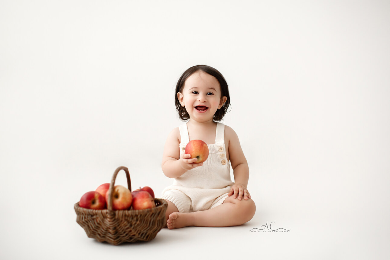 Stunning London Toddler Boy Pictures | portrait of an 18 months old toddler boy playing with red apples during a professional photoshoot