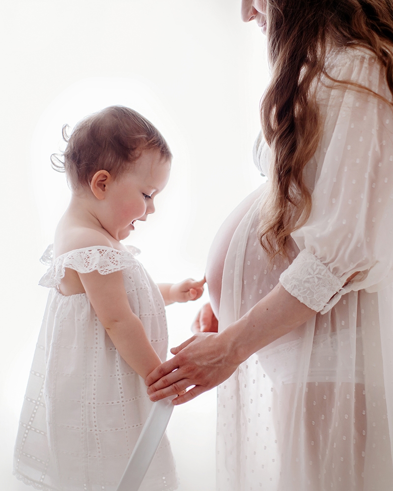 Beautiful London Mother's Day Mini Sessions | 2025 13 London Mother's Day Mini Sessions | toddler girl pointing to her mum's pregnant belly