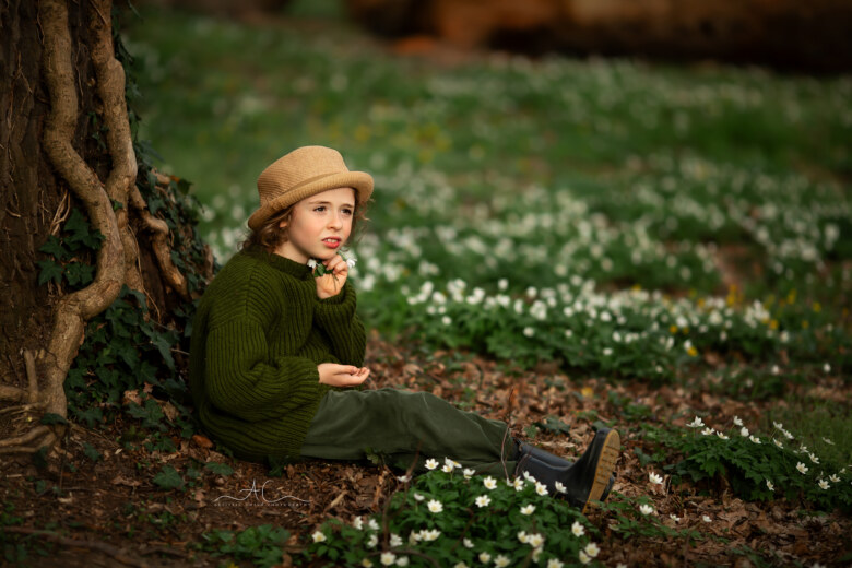 Best London Spring Child Photos | an 8 year old boy sitting under an old tree in the park and holding a bunch of white spring flowers