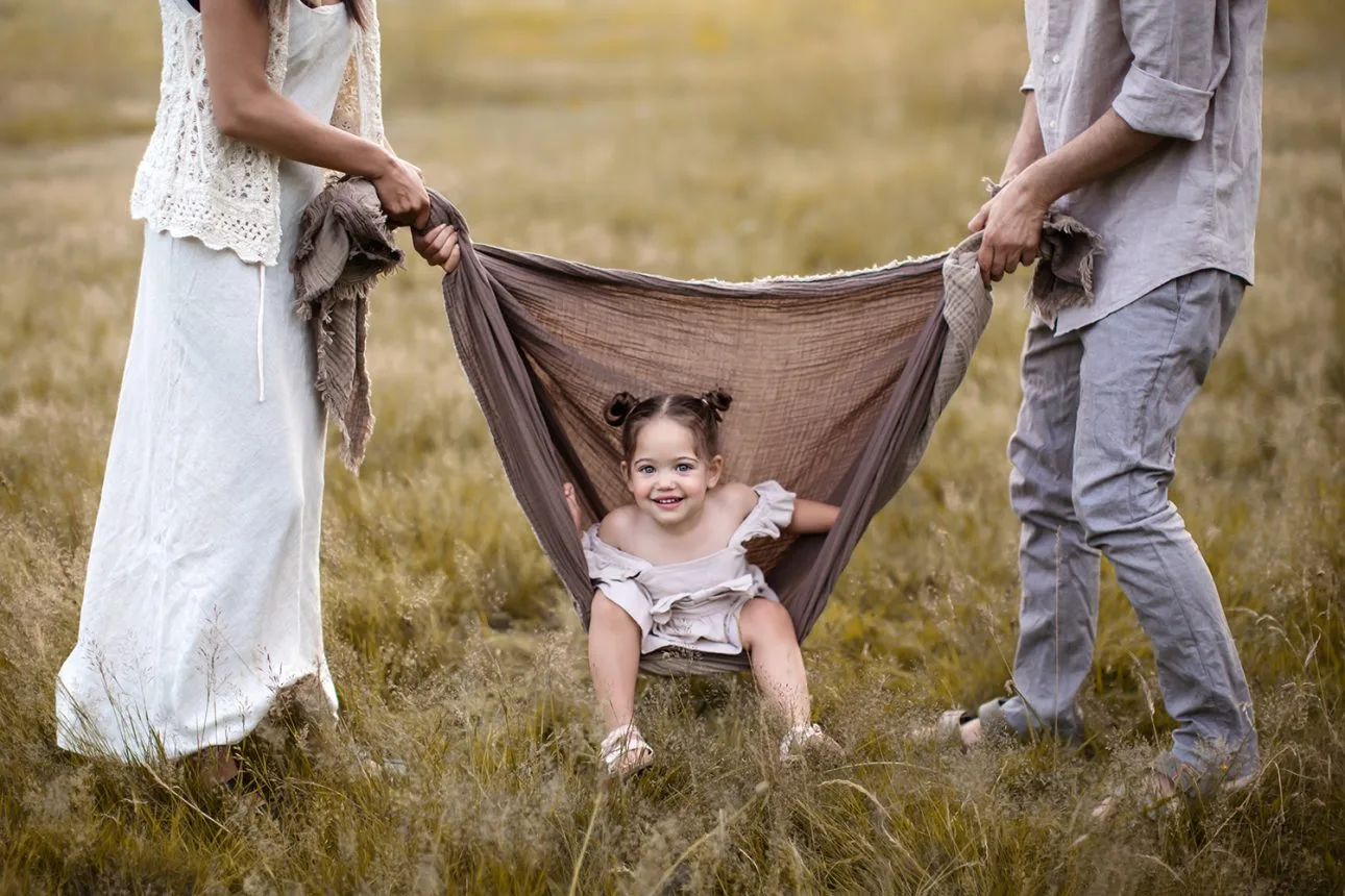 London Summer Family Minis | portrait of a little girl enjoying a swing in a blanket during a family session in a grass field in South East London
