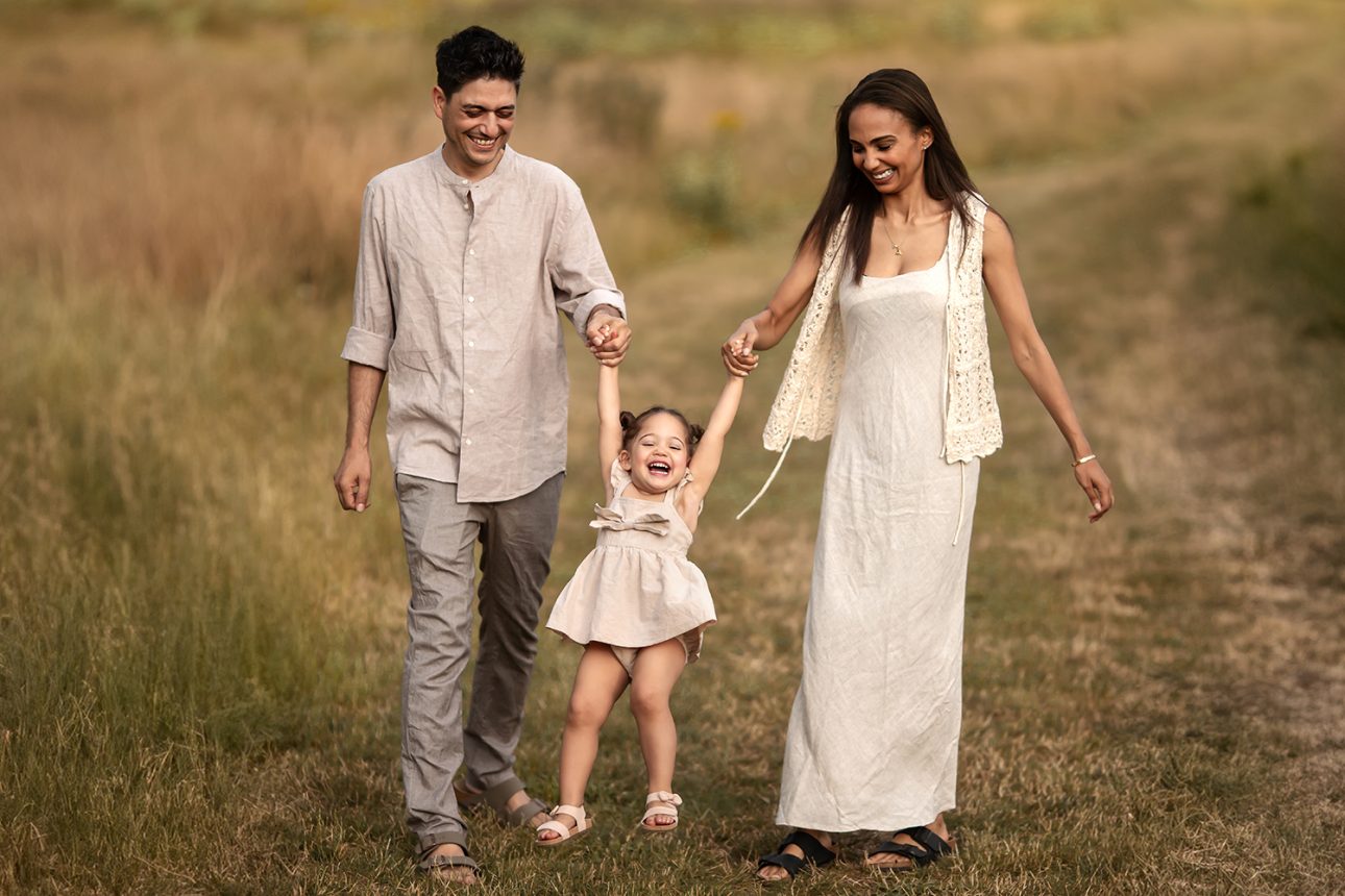 London Summer Mini Sessions | parents walking and swinging their 2 year old daughter