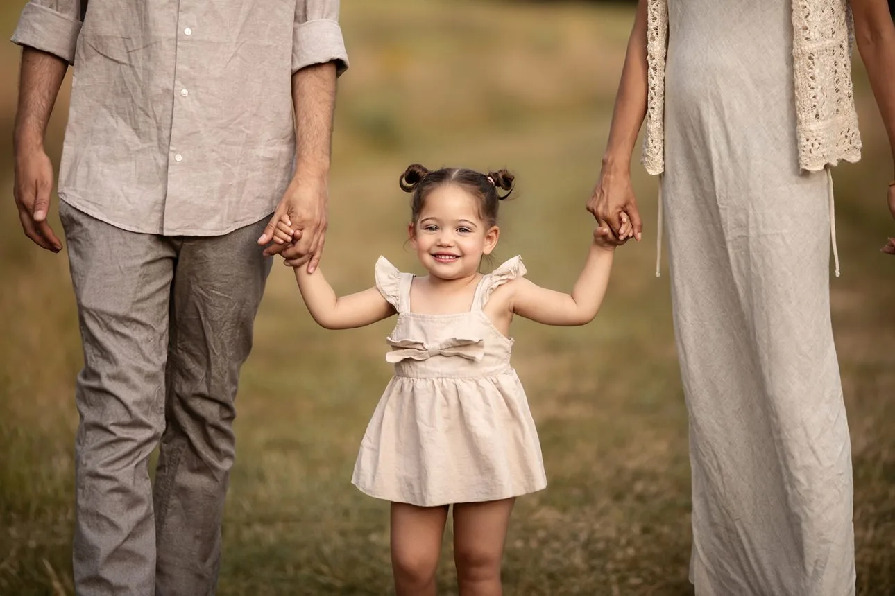 London Summer Mini Sessions | a close up portrait of a 2 year old girl holing Mum's and Dad's hands