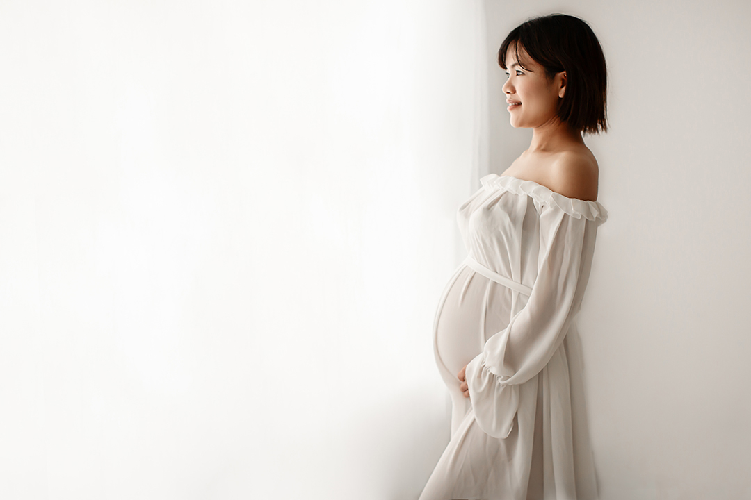 London Maternity Photography 9 London Maternity Photo Session | side portrait of a pregnant woman looking through the window and holding her belly