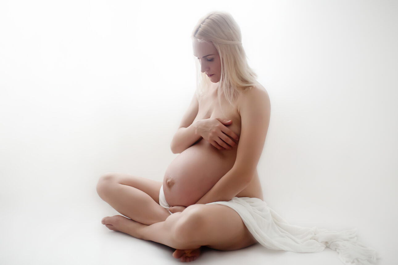 London Maternity Photography 15 London Maternity Photography | covered nudity backlit maternity portrait showing a pregnant woman sitting and looking at her belly