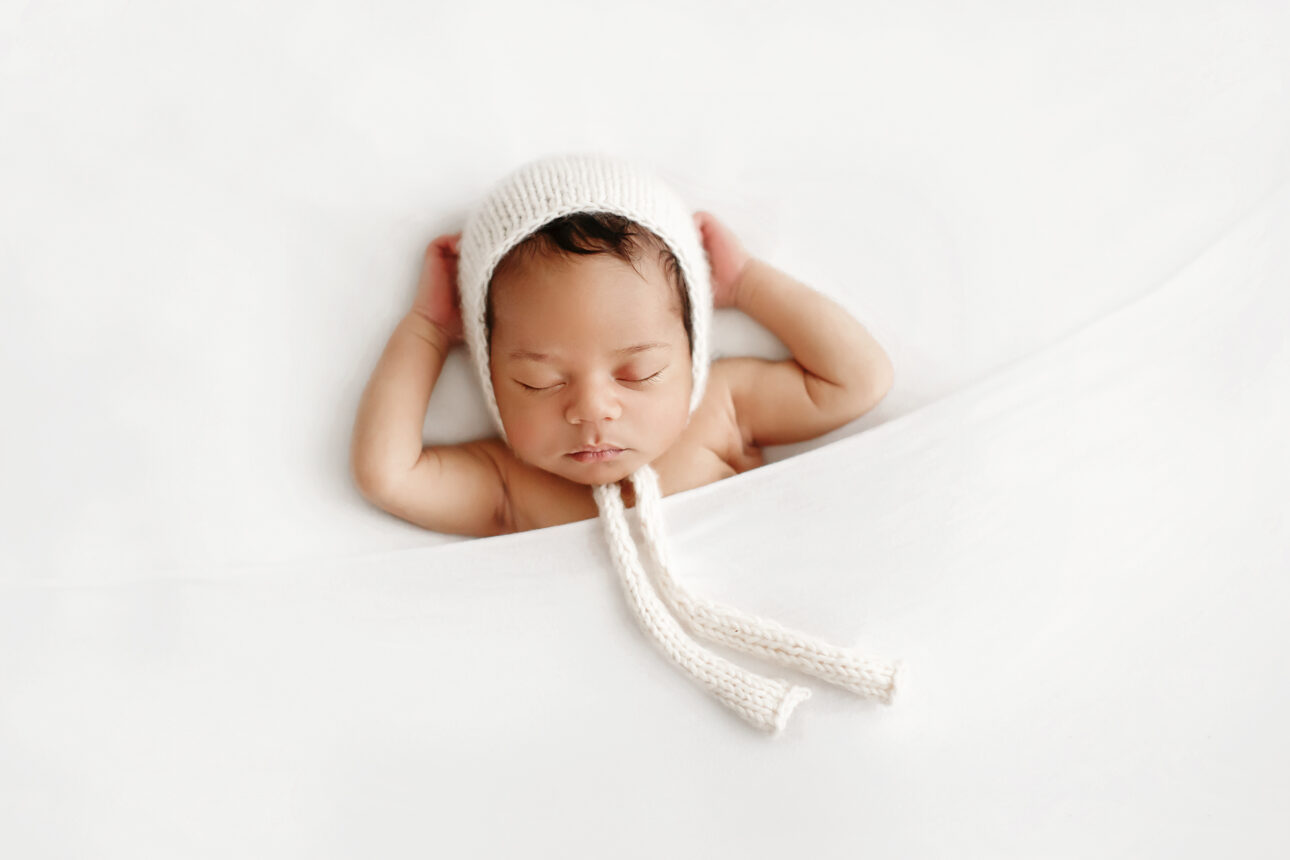 London Newborn Photography 30 London Newborn Photos | newborn baby boy sleeping on his back and wearing a cute bonnet