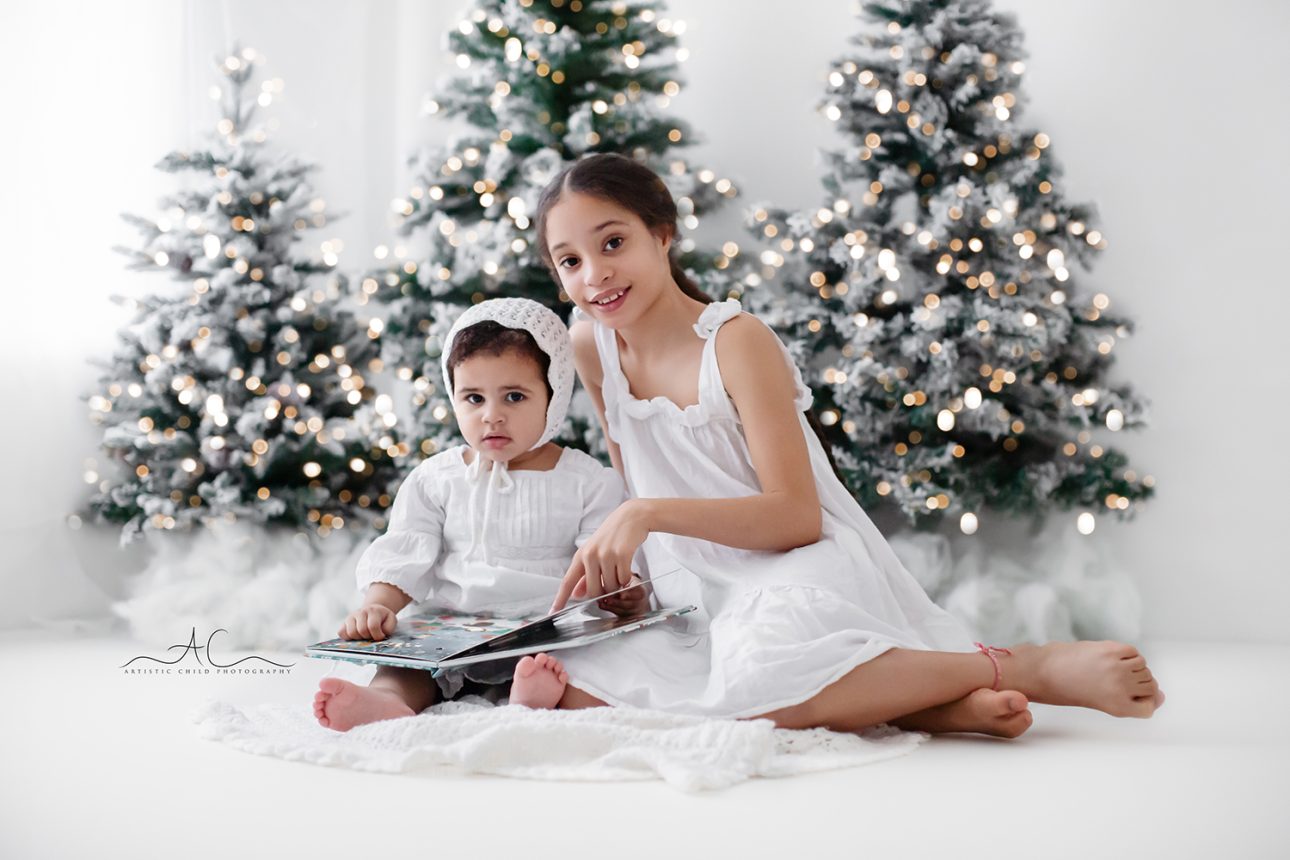 London Christmas Mini Sessions | portrait of sisters reading a Christmas book