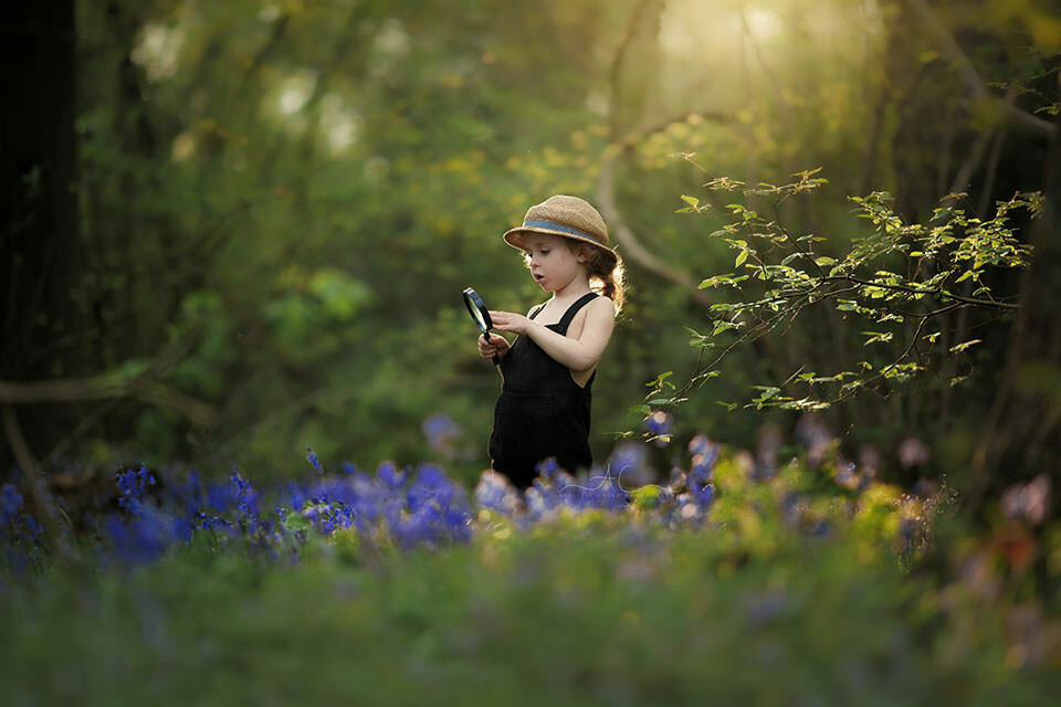 London Bluebell Mini Sessions | portrait of a boy wih a magnifying glass looking at the bluebells