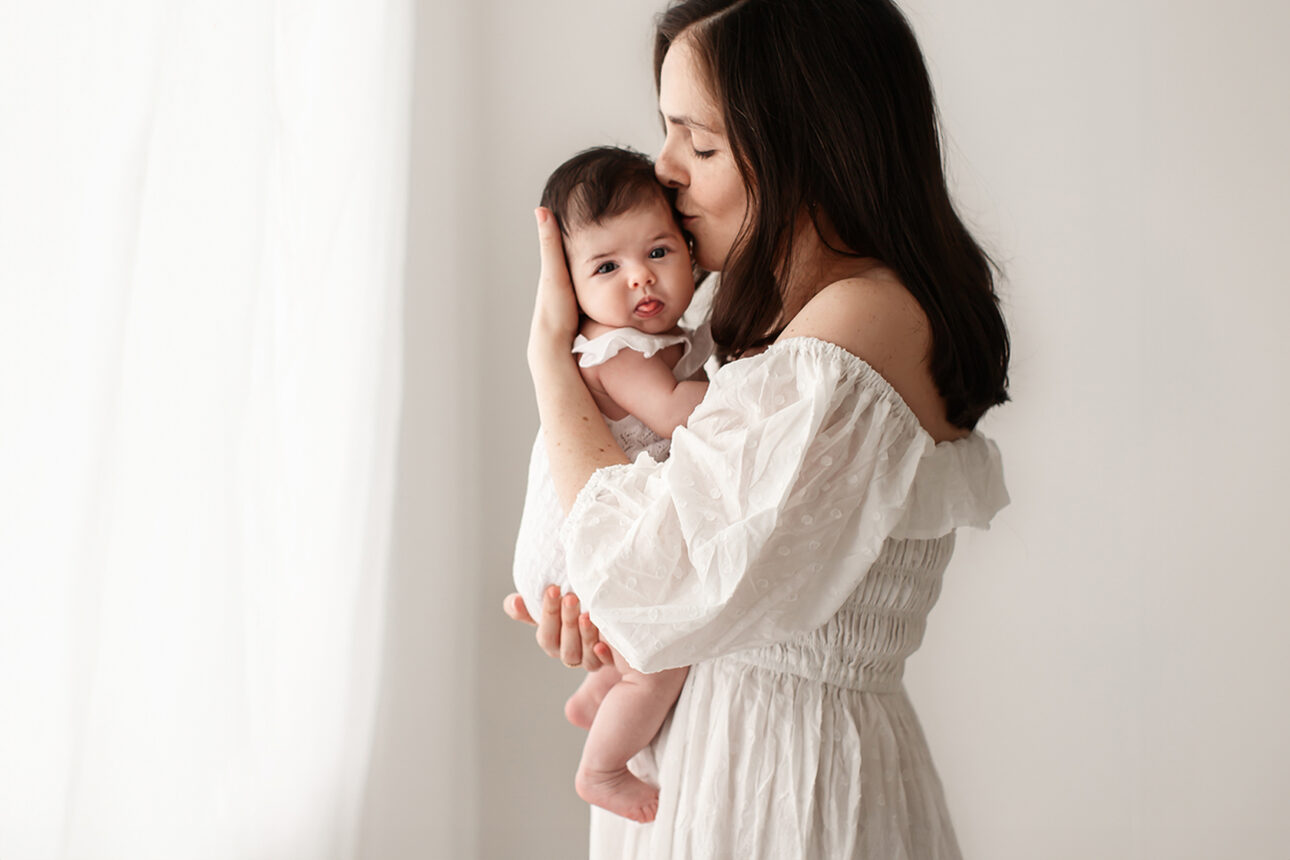 London Baby Milestone Photography | portrait of a mother kissing gently her 3 moths old baby girl during a baby photoshoot in South East London studio