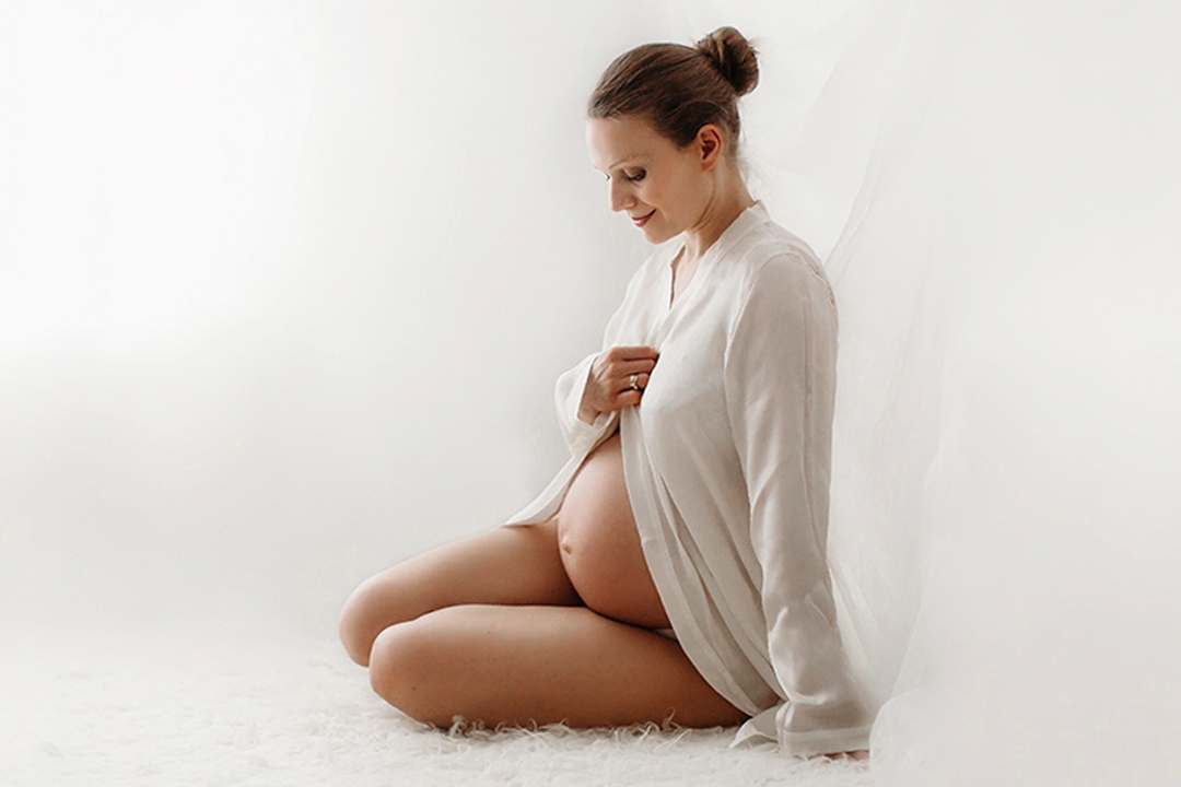 London Maternity Photography | Pregnant mother looking at her bump during studio maternity photography session in South East London.