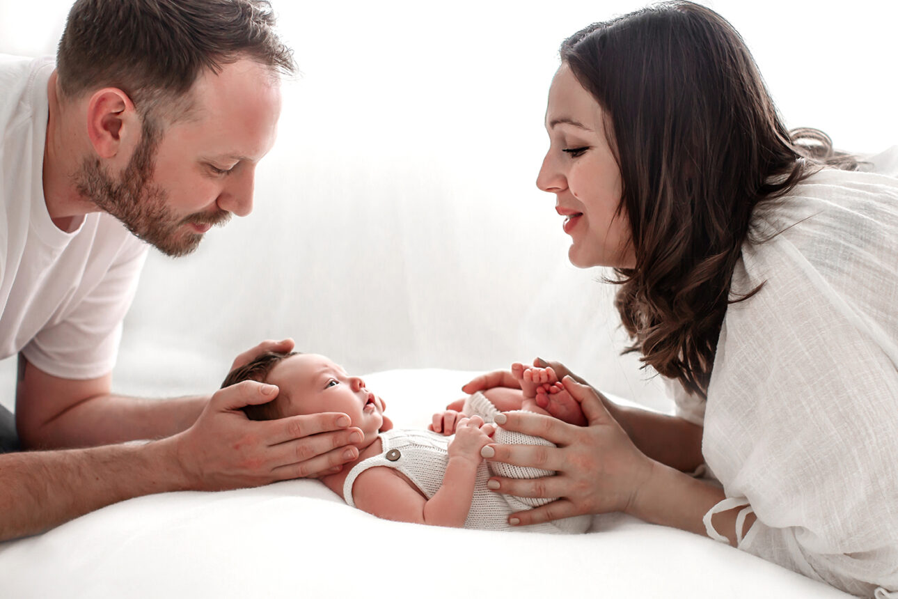 London Newborn Photography | a portrait of parents holding and looking at their newborn baby taken during a newborn photoshoot in South East London