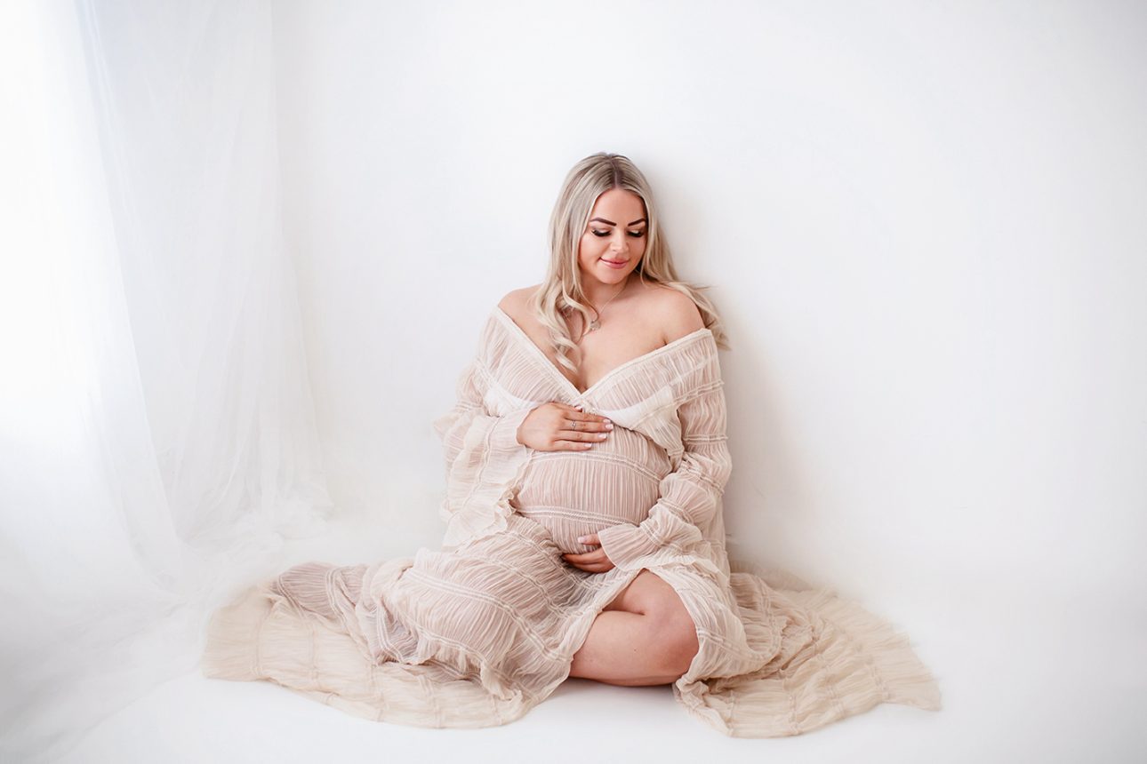 Bromley Maternity Photographer 22 Bromley Maternity Photoshoot | portrait of a mum to be sitting comfortably on the studio floor in a beautiful maternity dress